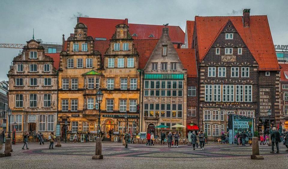 Historische Fachwerkhäuser auf einem Marktplatz in Bremen mit roten Dächern an einem belebten Platz bei bewölktem Himmel