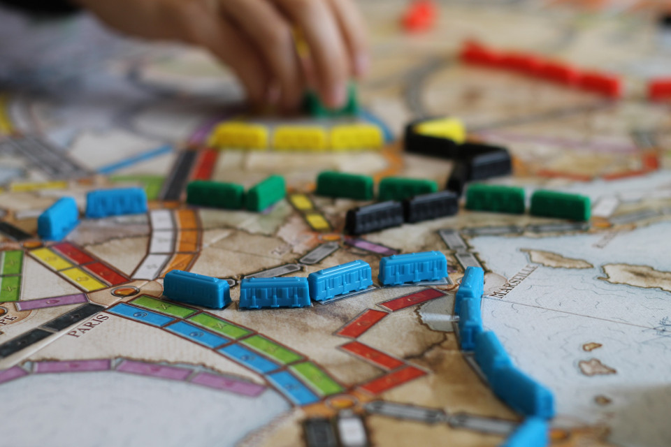 Auf einem Spielplan werden viele bunte Spielzeugzüge hin- und hergeschoben.