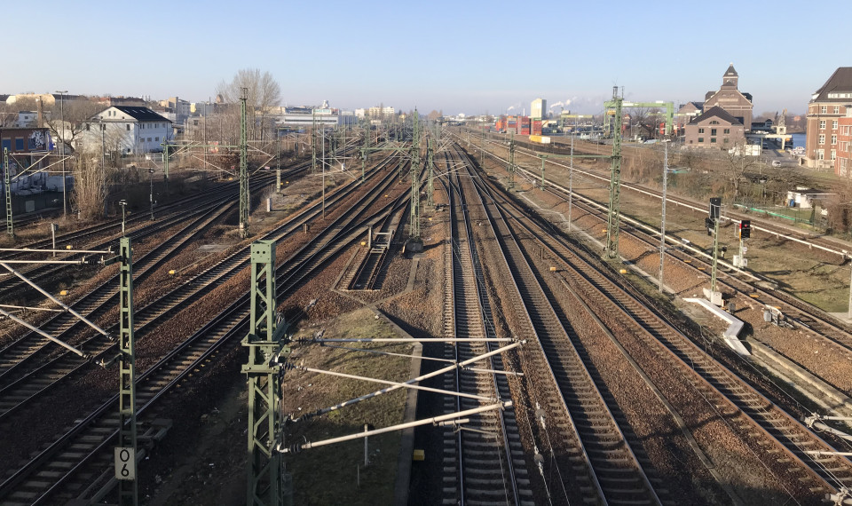 Blick von einer Brücke auf ein Gewirr aus Streckengleisen mit Oberleitung und Weichen, einem Bahnsteig und zahllosen Signalen.