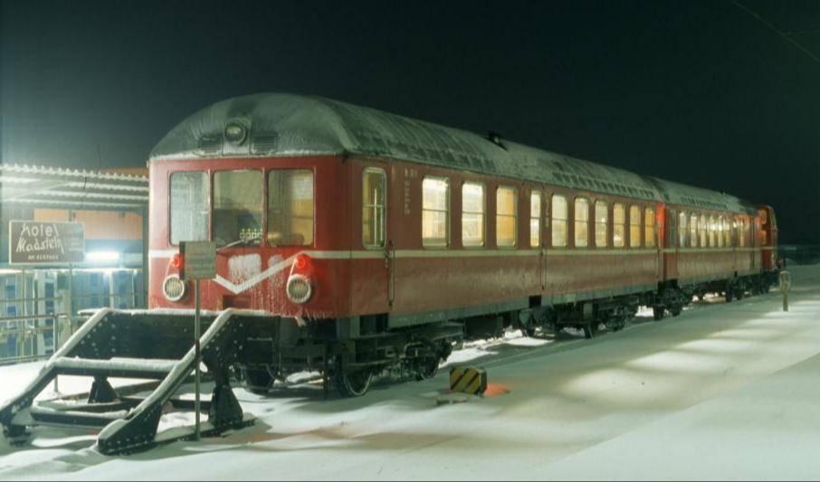 Ein abgestellter Wendezug, bestehend aus zwei Personenwagen und einer Diesellok im Winter.